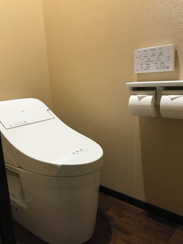 Toilet med kontrolpanel og papirhåndklædedispenser.