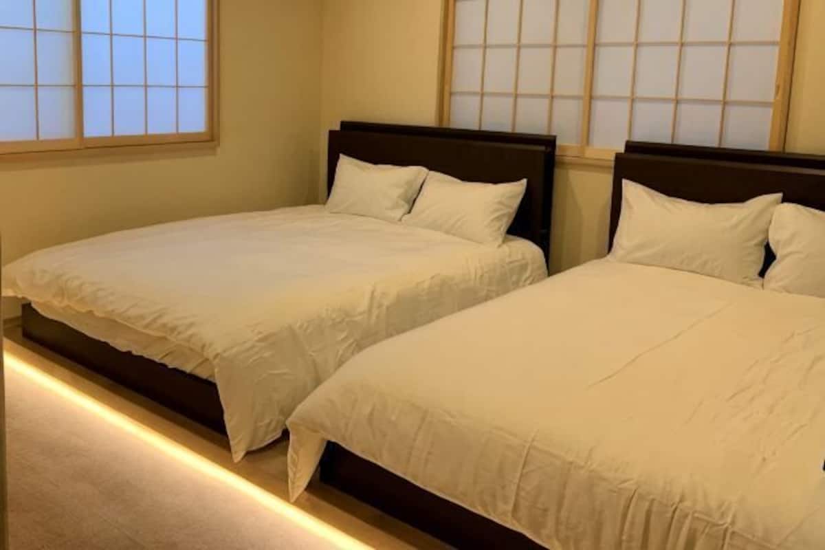 Two beds with wooden headboards in a room with large windows.