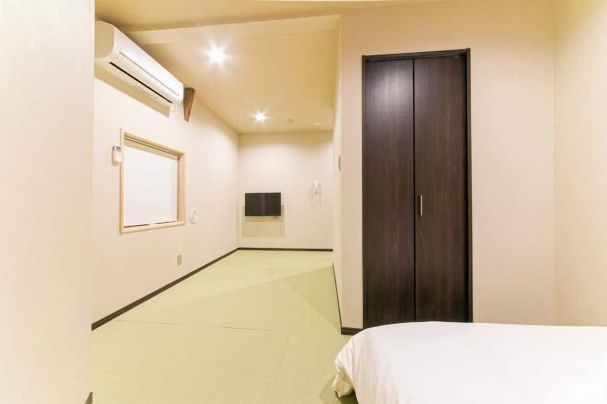 Habitación de hotel con cama, armario, espejo y aire acondicionado.