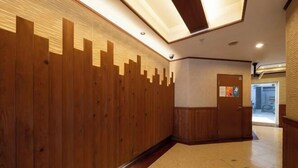 A hallway with wooden paneling, a door with a bulletin board, and a tiled floor. - Sharumu Biruzu Matsuyamachi (Osaka)