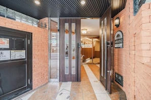 A hotel entrance with a reception desk, a glass door, and a sign indicating the hotel's name.