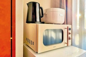 Un horno microondas con una cafetera y una cocedora de arroz encima.