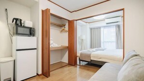 A compact hotel room with a bed, a small seating area, a microwave, and a closet. - Sharumu Biruzu Matsuyamachi (Osaka)