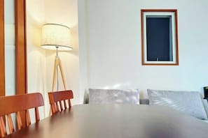 Una habitación con cama, mesa, sillas, lámpara y un cuadro en la pared.