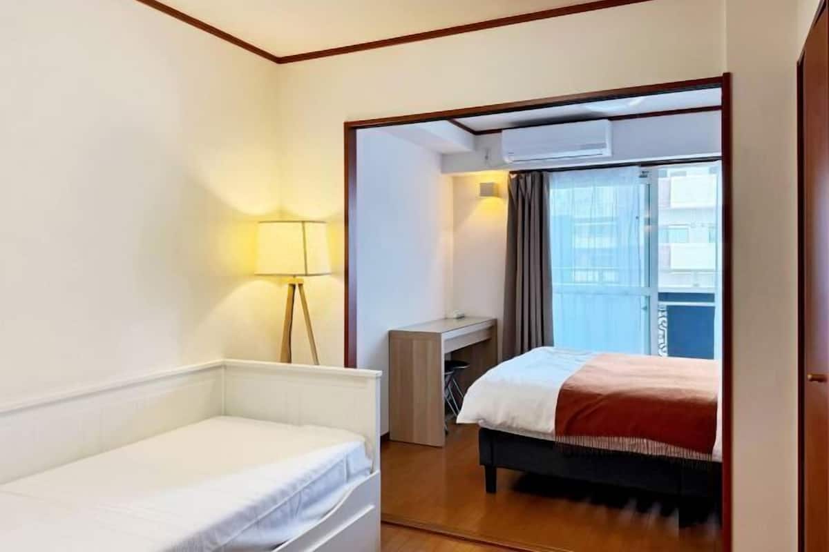 Habitación de hotel con cama, escritorio, lámpara y vistas al exterior.
