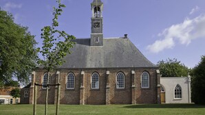 A church with a prominent clock tower, arched windows, and a brick facade.