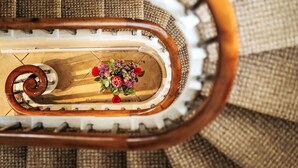 En spiraltrappa med ett träräcke och en blomsterdekoration längst ner.