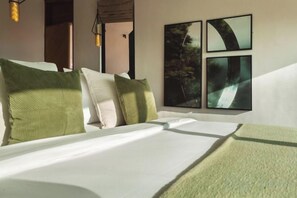 Una habitación de hotel con una cama, almohadas, un plaid verde y cuadros en la pared.