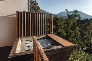 A wooden outdoor seating area with a view of a mountain and dense forest. - Aurora Cabins by Panoramika (Bali)