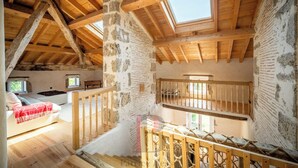 A rustic attic bedroom with exposed wooden beams, a stone wall, and a loft bed. - Large renovated house, ideal for a large family looking for peace and quiet. (Fargues-sur-Ourbise)