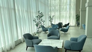 A modern lounge area with a round table, several blue chairs, and potted plants. - Tri Tower Residence (Walk 3 minutes to Malaysia & Singapore customs) (Johor Bahru)