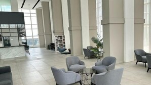 A spacious lobby with grey armchairs, a glass coffee table, and a bookshelf. - Tri Tower Residence (Walk 3 minutes to Malaysia & Singapore customs) (Johor Bahru)