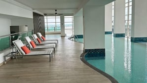 A poolside area with lounge chairs and a view of the ocean. - Tri Tower Residence (Walk 3 minutes to Malaysia & Singapore customs) (Johor Bahru)