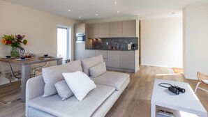 A modern living room with a sofa, a coffee table, and a dining area with a table set for two. - Wonderful private villa for 4 people with WIFI, TV and terrace (Veere)