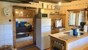 Una cocina acogedora con refrigerador, microondas y armarios de madera. Se ve un pequeño comedor con una mesa y sillas.