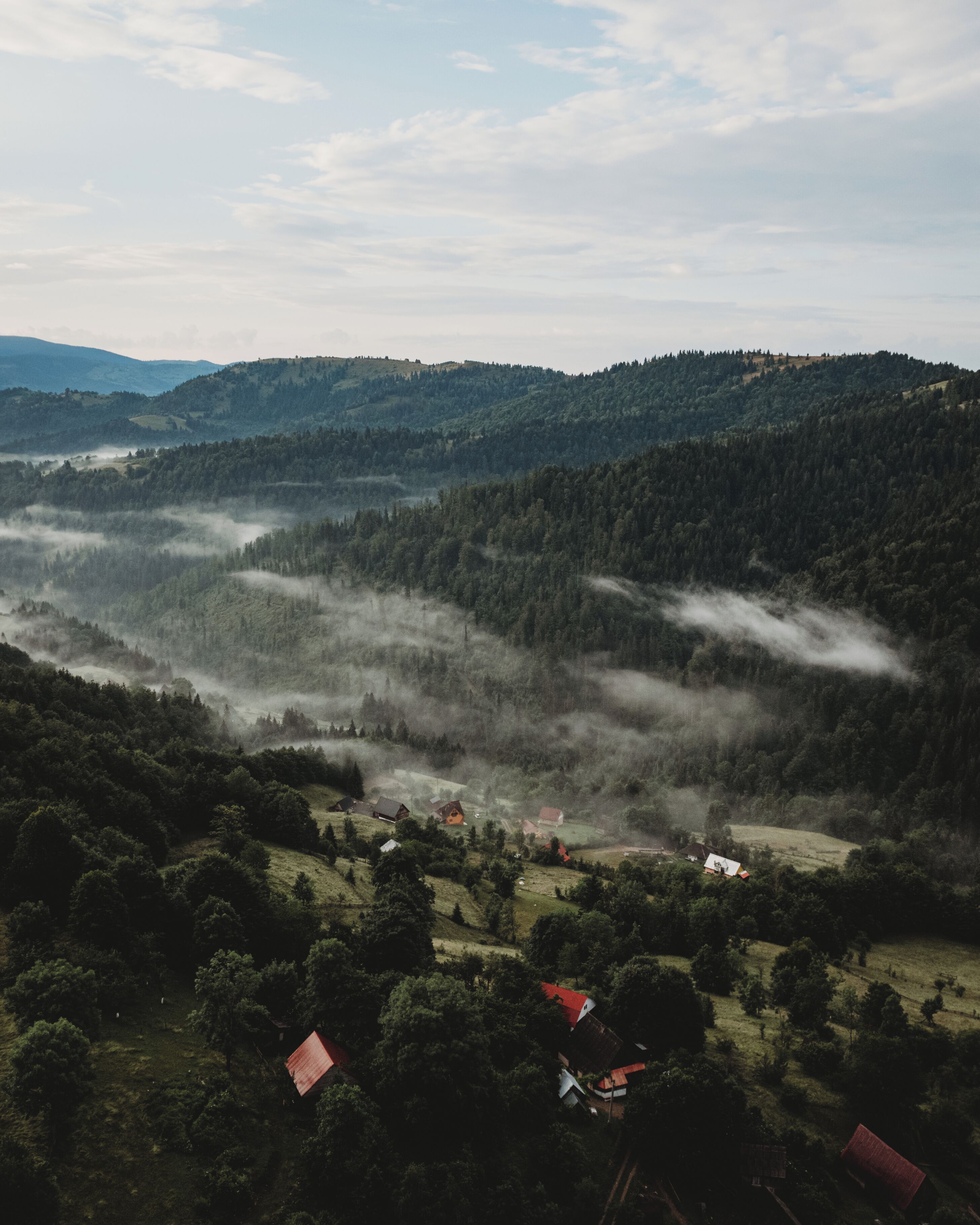 A mountainous landscape with scattered houses and dense forest.
