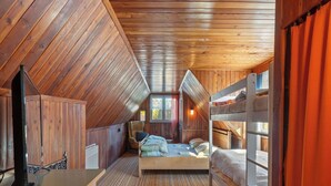 Une chambre mansardée chaleureuse, avec un lit superposé, un bureau et une chaise.
