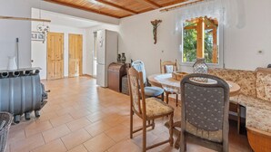 Un vaste espace de vie doté d’un plafond en bois, d’une table à manger avec des chaises, d’un canapé et d’une fenêtre donnant sur un paysage verdoyant.