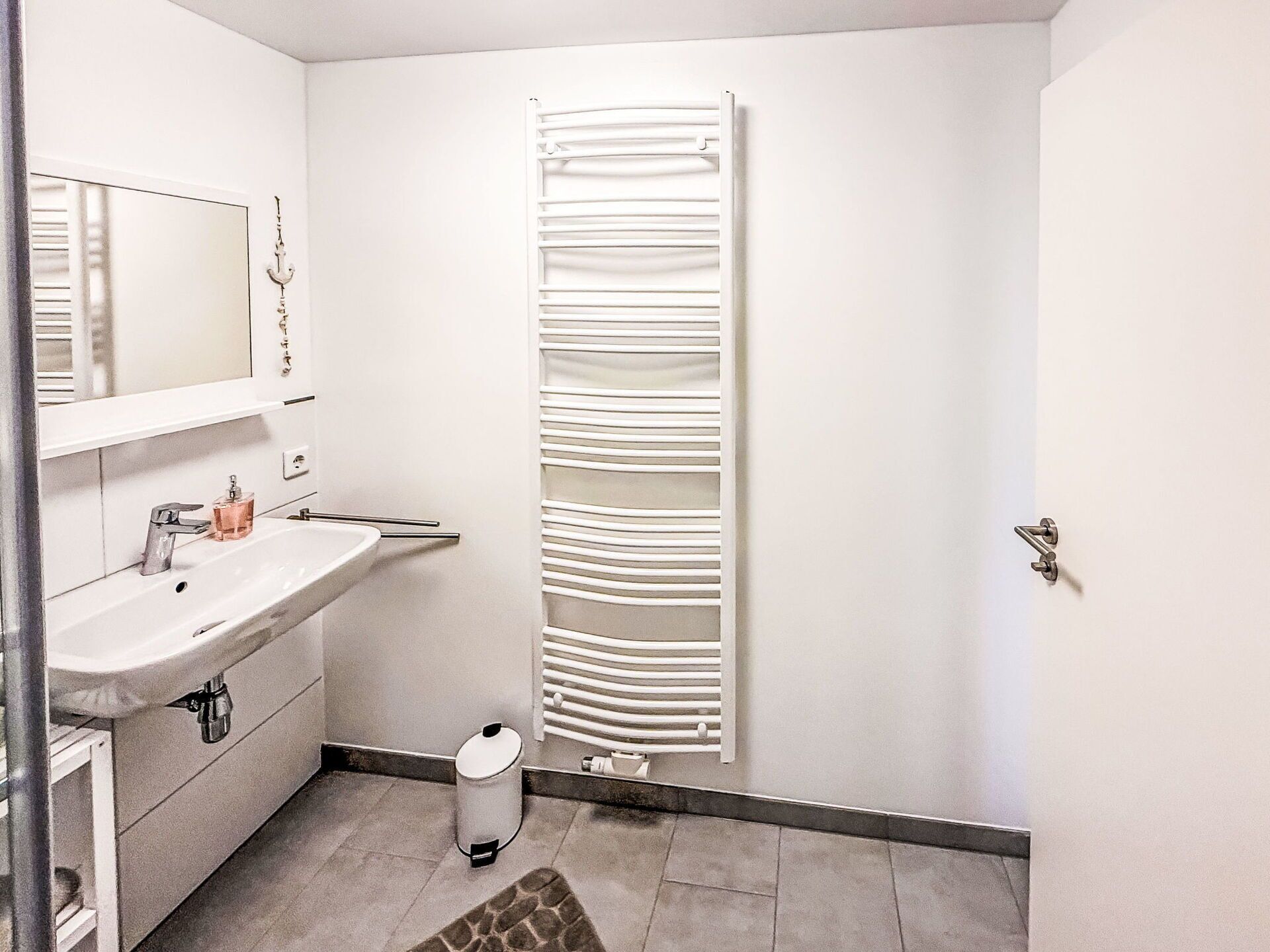 Ein modernes Badezimmer mit Waschbecken, Spiegel und Handtuchhalter.