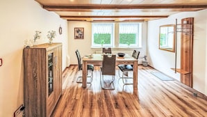 Un coin repas comprenant une table et des chaises en bois, un buffet en bois et une fenêtre donnant sur un paysage verdoyant.