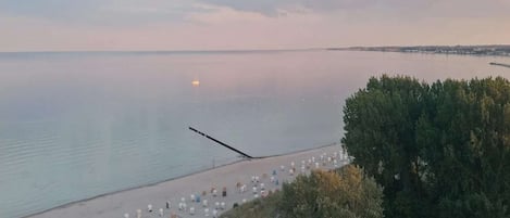 A beach with rows of white tents and a pier extending into calm waters.