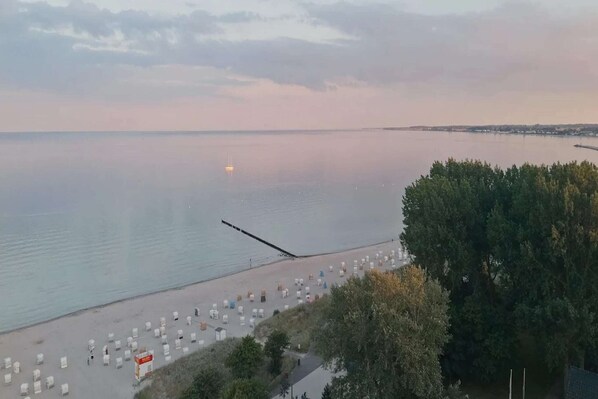 A beach with rows of white tents and a pier extending into calm waters.