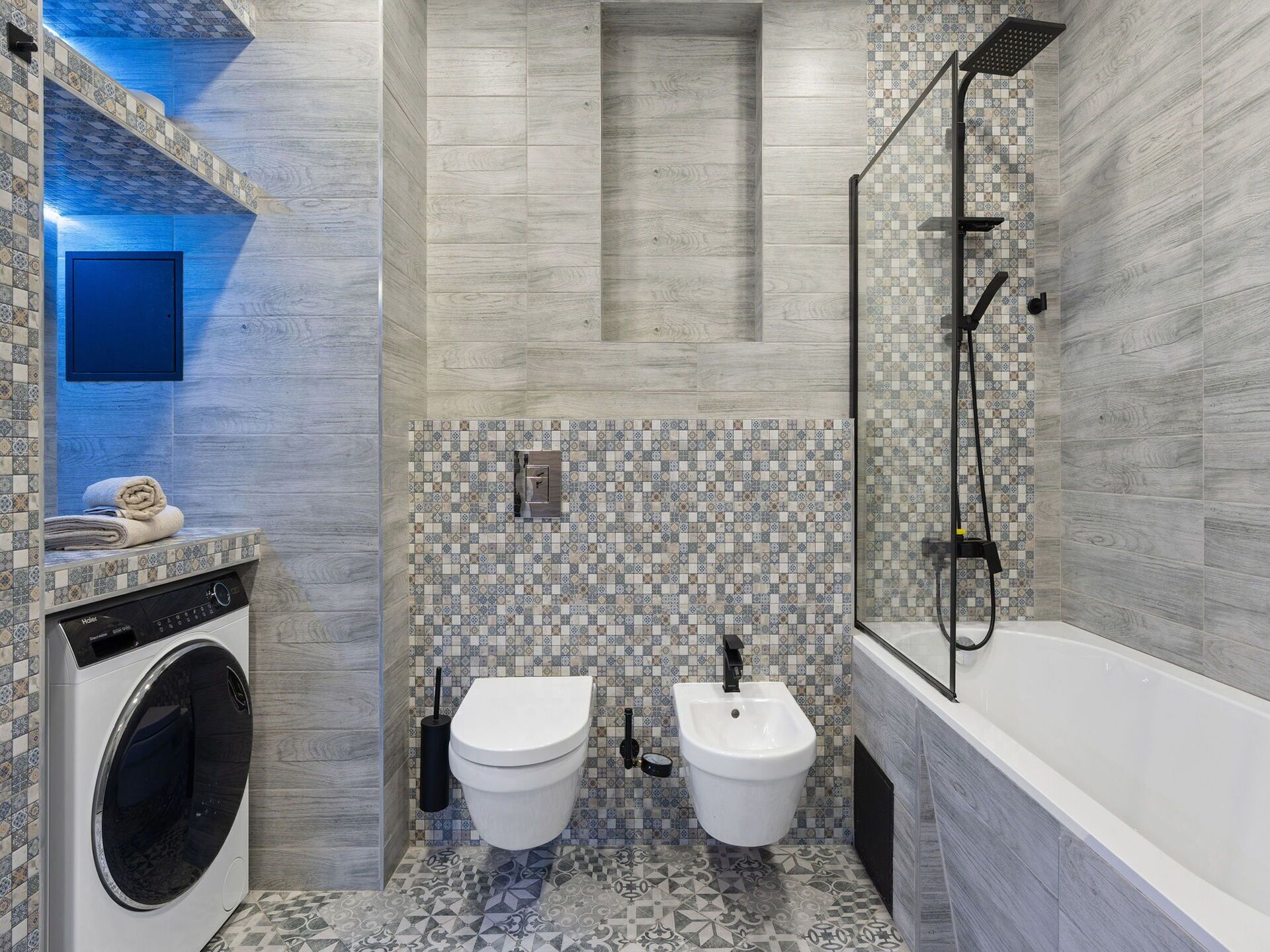 A modern bathroom with a washing machine, two toilets, a bidet, and a shower.