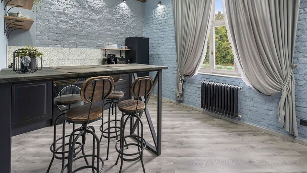 Uma cozinha com design rústico, com paredes de tijolos aparentes, vigas de madeira e um espaço bar com banquetas.