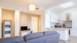 Una sala de estar moderna con un sofá gris, una televisión y un escritorio pequeño con una computadora.