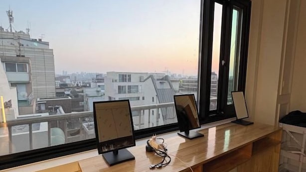 A modern office space with a long wooden desk, two monitors, and a pair of glasses on the desk. - K Wave Guesthouse Ony Female In Hongdae 2 (Seoul)