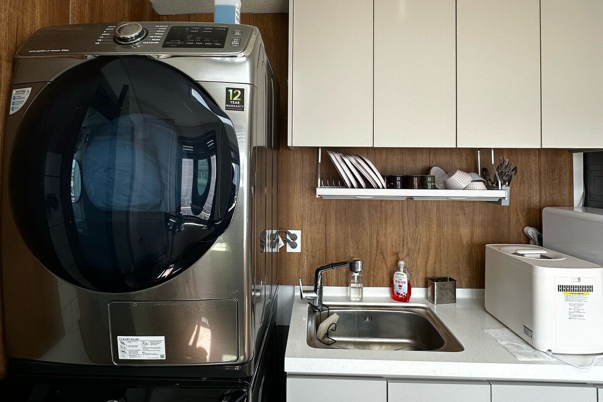 A compact kitchen with a washing machine, a microwave, and a sink.