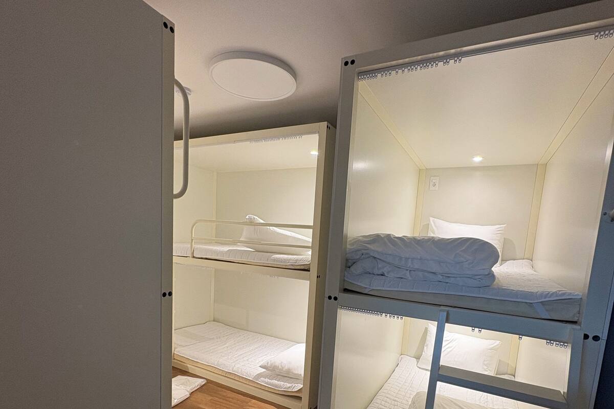 A room with two bunk beds, wooden flooring, and a white door.