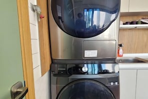 Una lavatrice Samsung in cucina, con un pensile in legno e un lavandino in acciaio inossidabile.