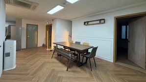 A conference room with a wooden table and chairs, a whiteboard, and a door leading to another room. - K Wave Guesthouse Ony Female In Hongdae 2 (Seoul)