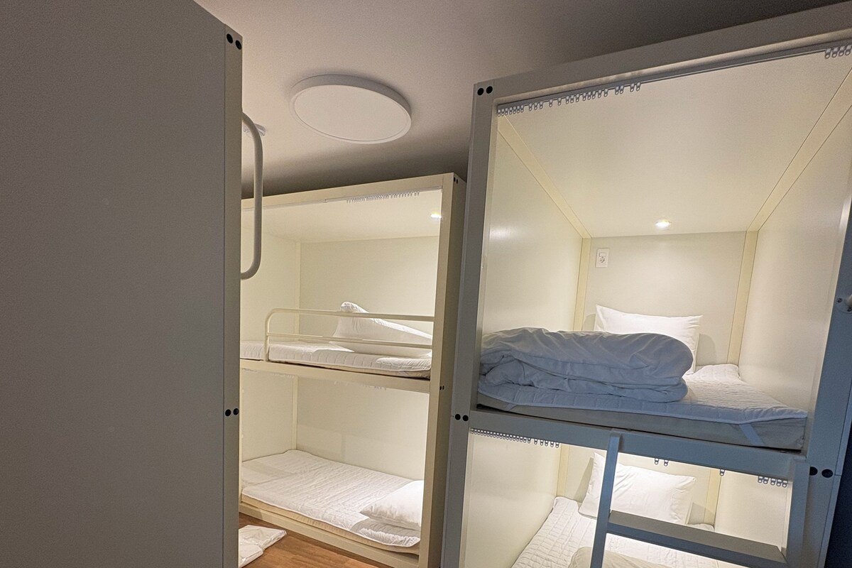 Ein Zimmer mit zwei Etagenbetten, Holzboden und einer weißen Tür.