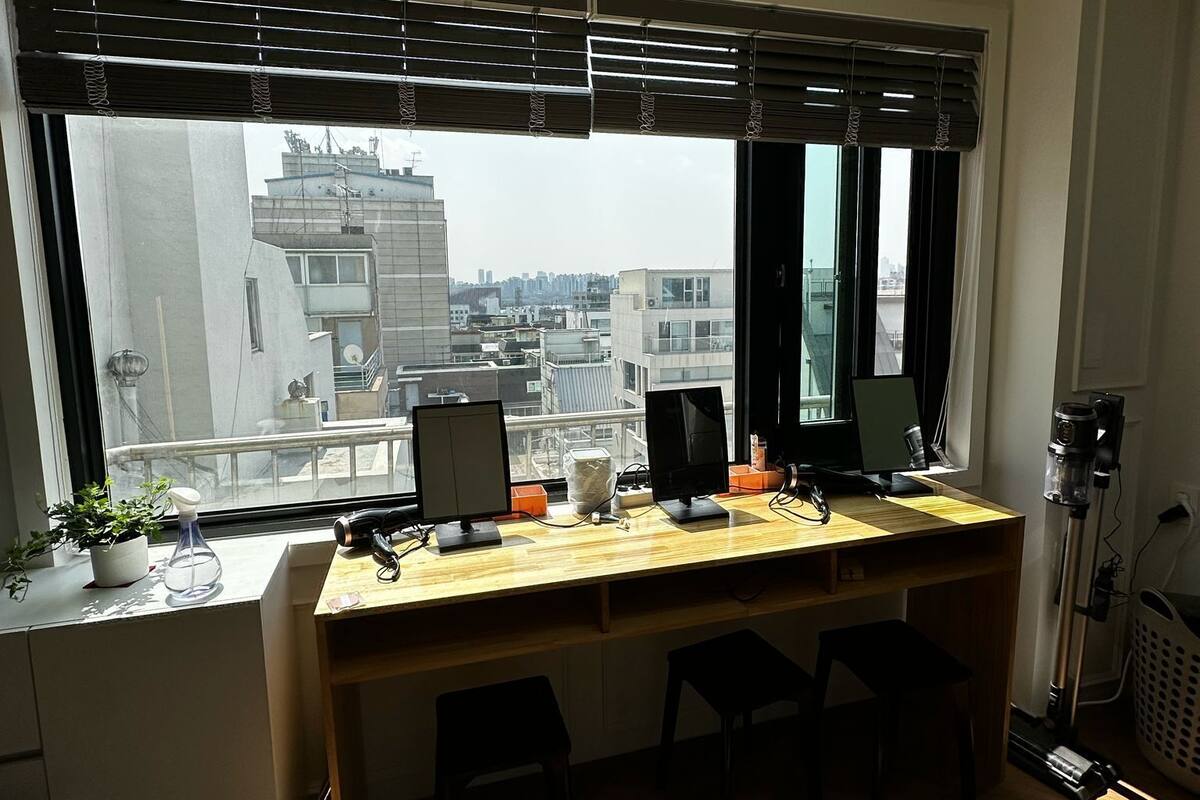 A modern office space with a large desk, two monitors, and a camera on a tripod.
