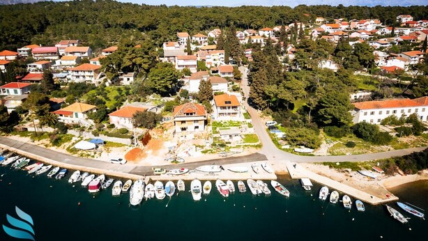 An aerial view of a coastal village with houses, a marina with boats, and a mountainous backdrop. - Hvar spa & apartment-2 Bedroom-Terrace/Sea View 4 (Vrboska)