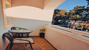 A small balcony with a round table and two chairs, a potted plant, and a view of trees and buildings. - Hvar spa & apartment-2 Bedroom-Terrace/Sea View 4 (Vrboska)
