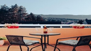 Une terrasse avec deux chaises et une table, une bouteille de vin et deux verres.
