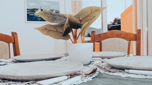 Une table à manger dressée avec des assiettes, des couverts et une plante en pot.