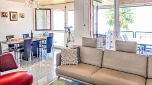 Una sala de estar moderna con sofá, mesa de comedor, sillas y un ventanal grande.