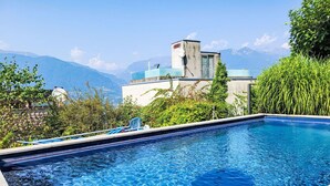 Una piscina con agua azul cristalina, rodeada de vegetación y vistas a montañas.
