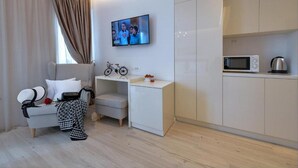 A modern living room with a sofa, a small table, a bicycle, and a TV mounted on the wall. - Via Porto Rooms - Deluxe Double Room with Double Bed and Balcony (Split)