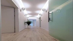 A hallway with light wooden flooring, white walls, and wall-mounted lighting fixtures. - Via Porto Rooms - Deluxe Double Room with Double Bed and Balcony (Split)