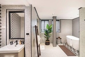 A modern bathroom with a large mirror, a sink, a bathtub, and a potted plant. - Soho Heritage House Chinatown Bangkok (Bangkok)