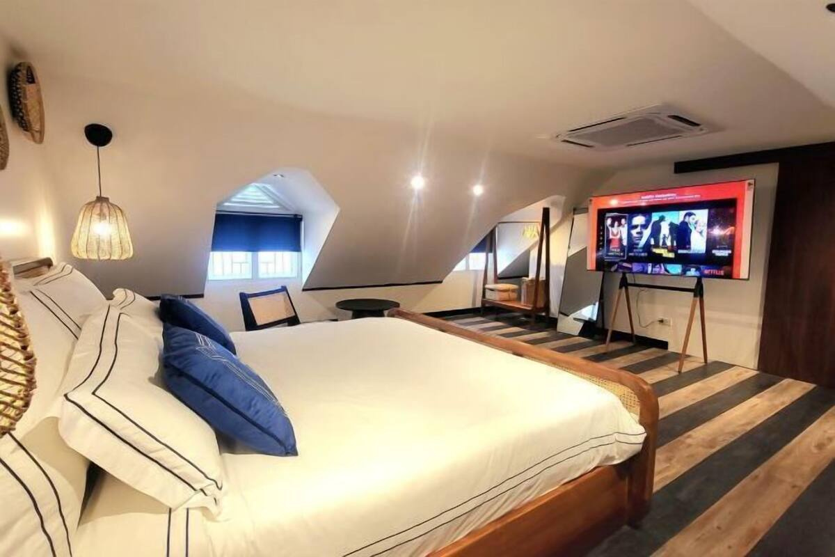 Un dormitorio con cama, televisor y escalera.
