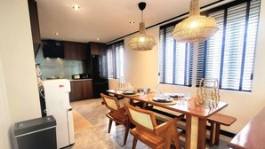 Un coin repas avec une table en bois, des chaises et une cuisine en arrière-plan.