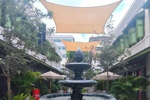 Une cour intérieure avec une fontaine centrale, entourée de bâtiments et de verdure.