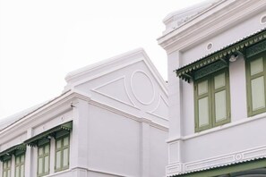 Une façade d’immeuble avec des encadrements de fenêtres verts et des murs blancs.