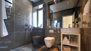 Un baño moderno con cabina de ducha de vidrio, inodoro, lavabo con tocador y espejo.
